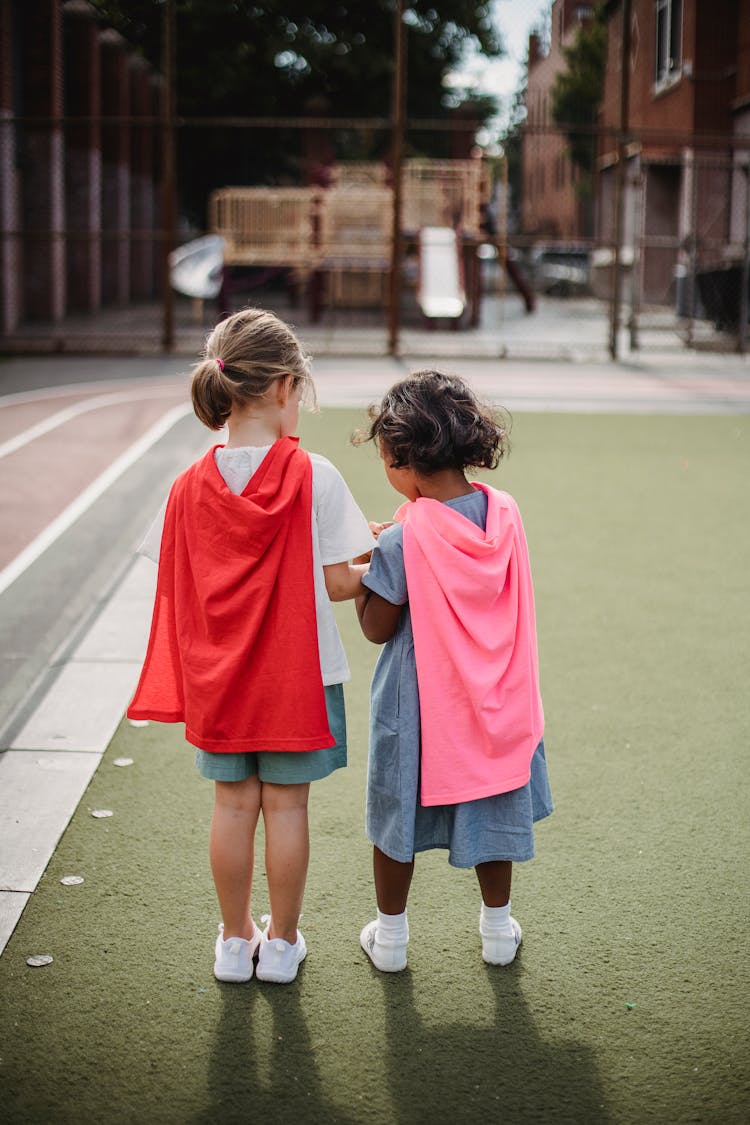 Little Girls Wearing Capes And Holding Hands 