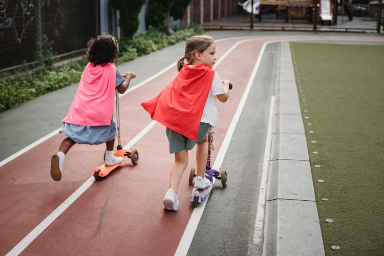 Little Girls Riding Scooters On Running Track