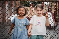Girl in White and Pink Floral Crew Neck T-shirt Standing Beside Gray Metal Fence