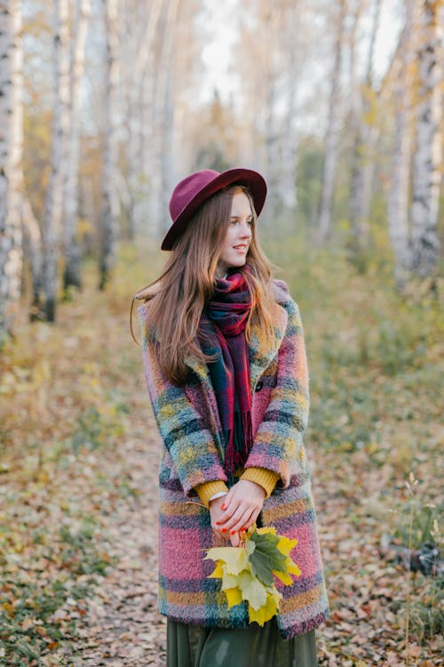 Gratis Mujer En Suéter Verde Rojo Y Amarillo De Pie En El Bosque Foto de stock