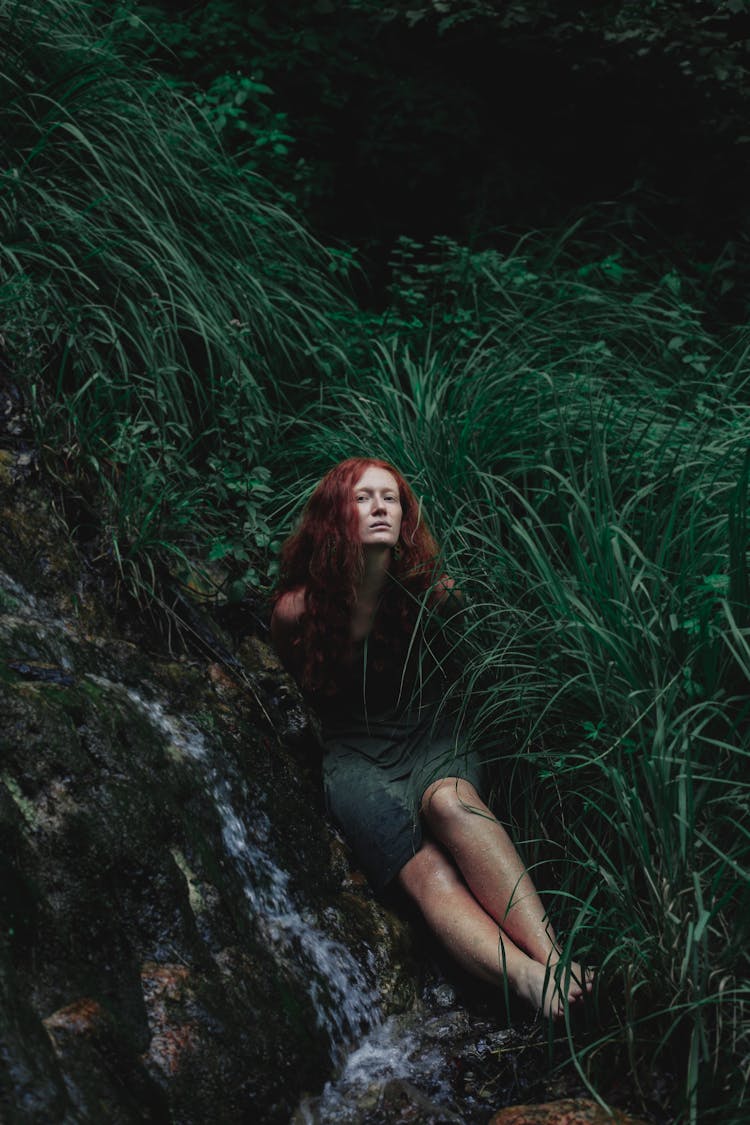 Woman In Dress Sitting Near Waterfall