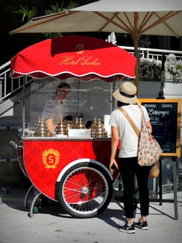Street vendor selling ice cream from a vibrant red cart in Salzburg, Austria.