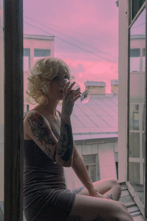 Young woman drinking on windowsill