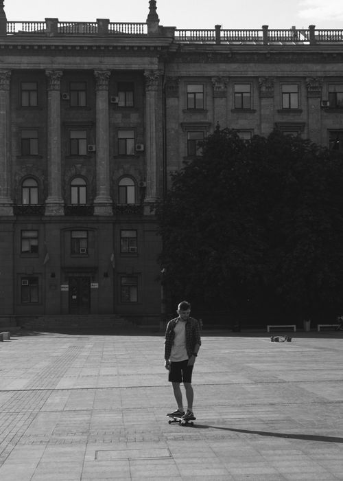 Free Young skateboarder in monochrome near a historical building, creating an urban lifestyle mood. Stock Photo