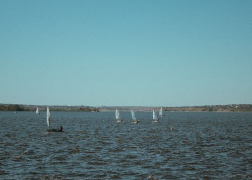 Free A serene view of sailboats gliding over calm waters under a clear blue sky, capturing a tranquil outdoor scene. Stock Photo
