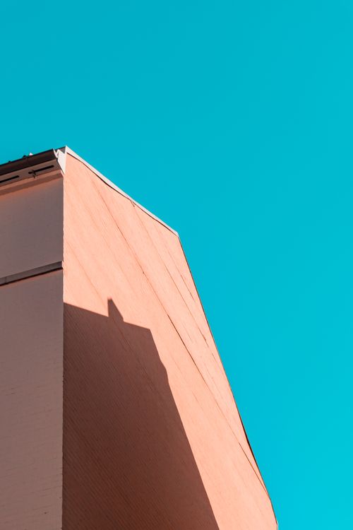 Free A minimalist building facade with geometric shadows set against a vibrant turquoise sky. Stock Photo
