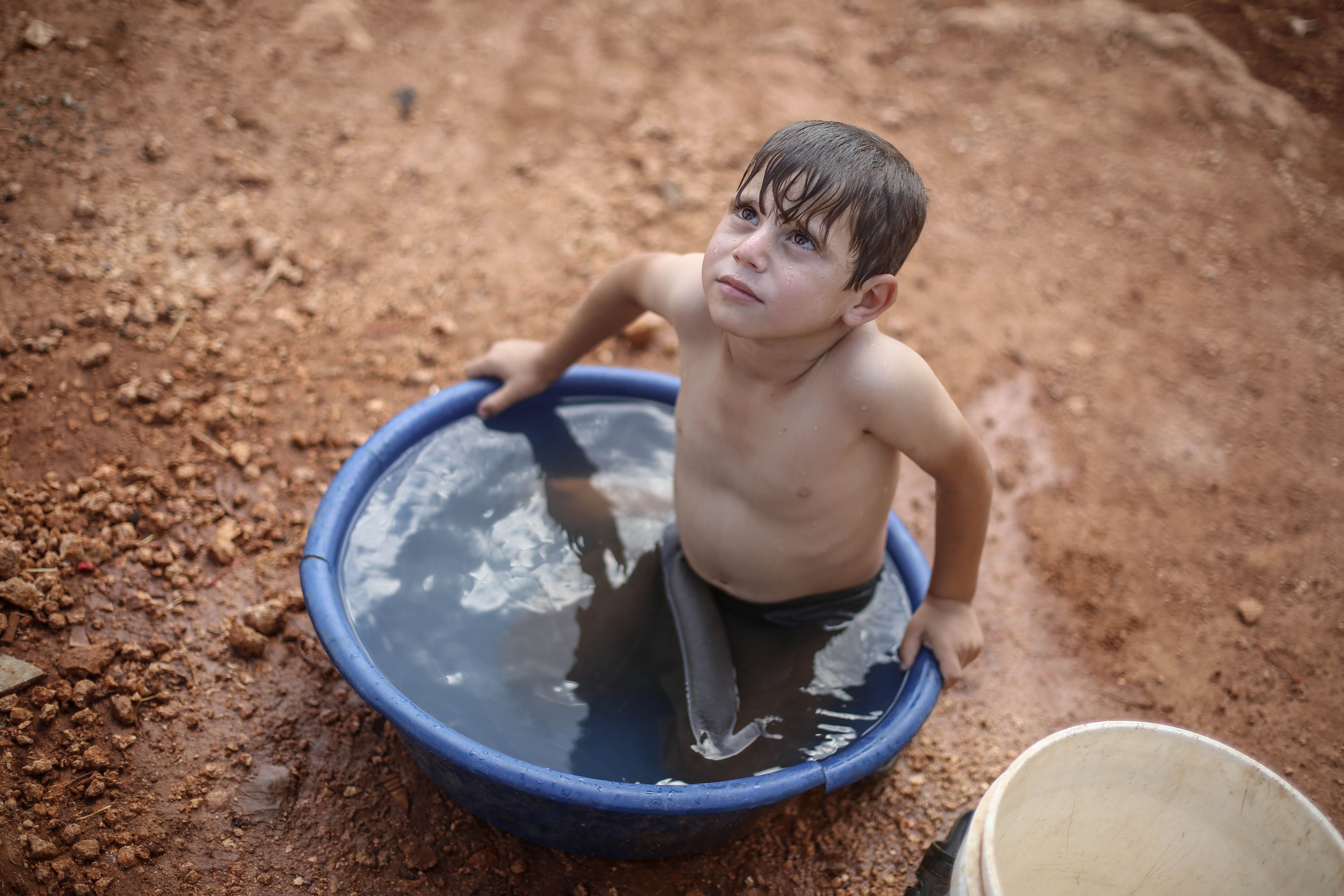 A Boy Taking a Bath in a Plastic Basin · Free Stock Photo
