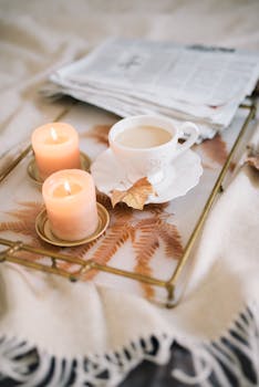 Warm scene with coffee, candles, and newspapers on a tray, perfect for autumn mornings.