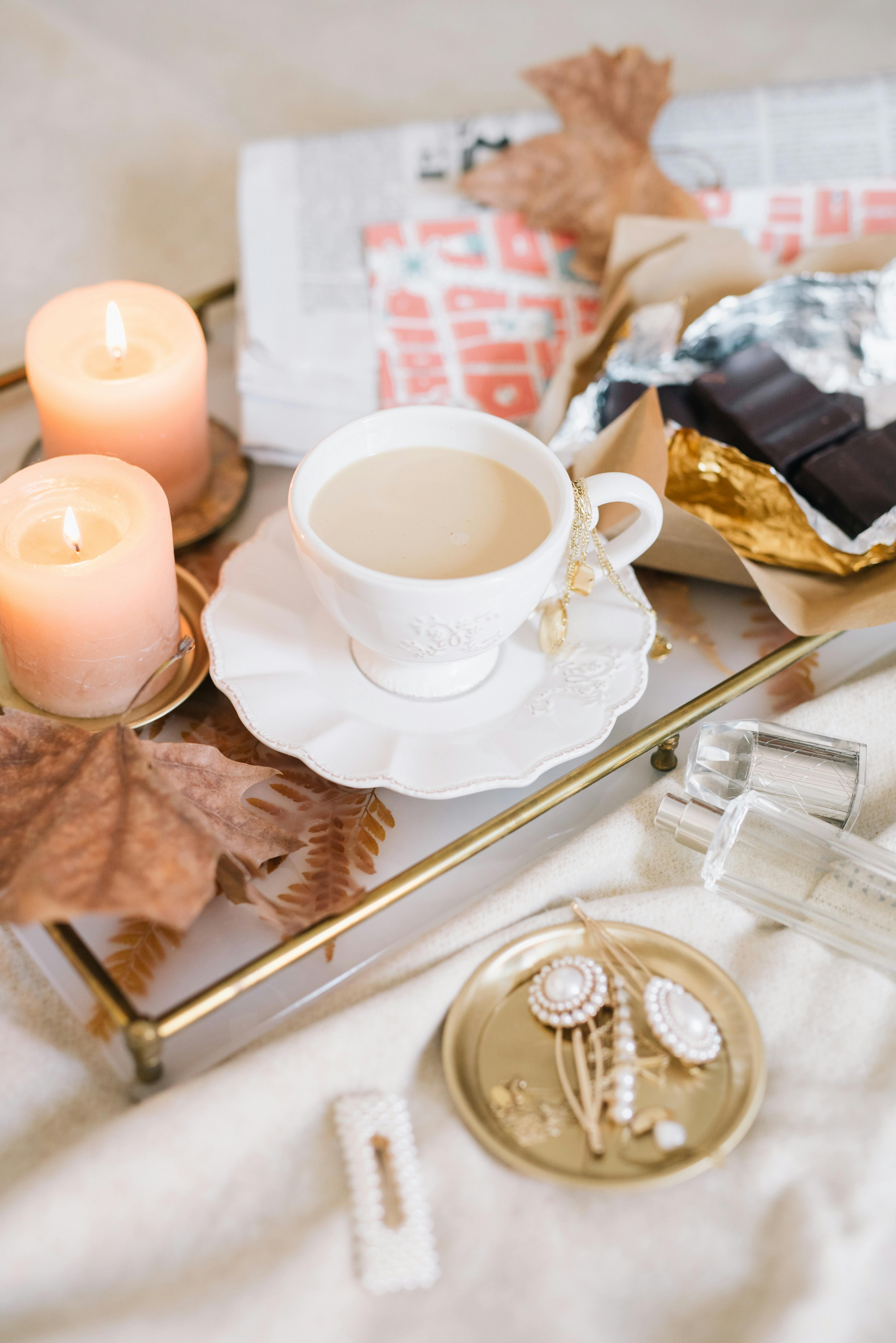 温暖的秋季早晨，托盘上摆放着咖啡、巧克力、蜡烛和报纸