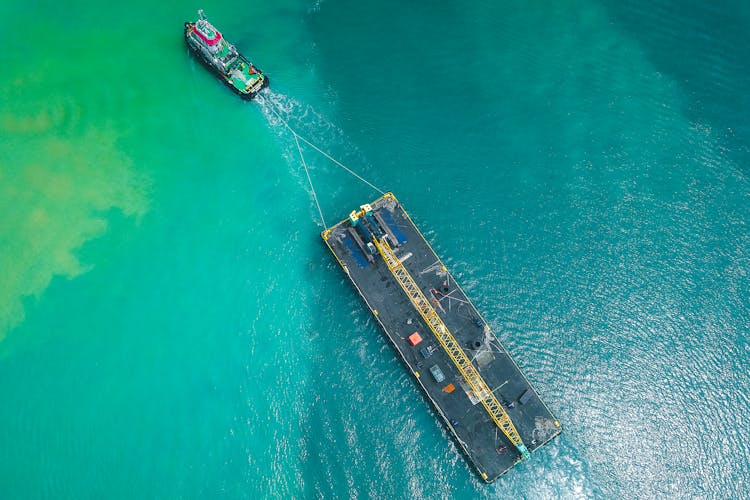 Motorboat Floating On Seawater And Pulling Big Platform