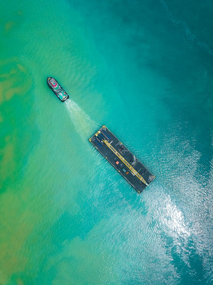 Aerial View Of Boat Pulling Big Shipment Platform On Seawater