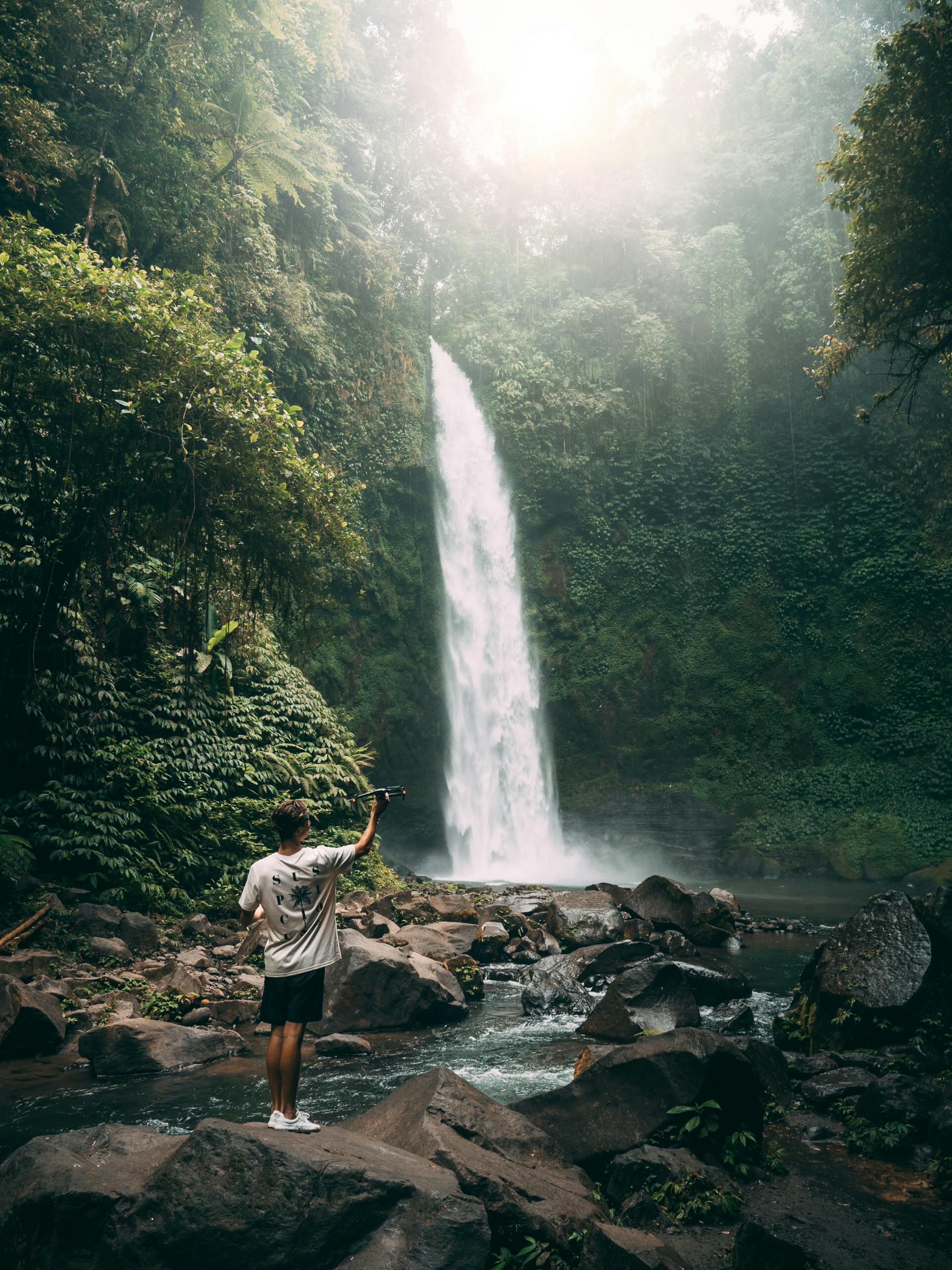 a person holding a drone while in the rainforest