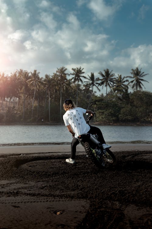 Homem De Camisa Branca Andando De Motocicleta Na Praia