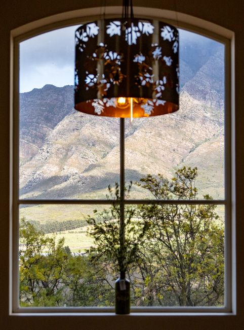 Photo by Magda Ehlers on Pexels A beautiful landscape view of mountains through a decorative glass window with a hanging light.