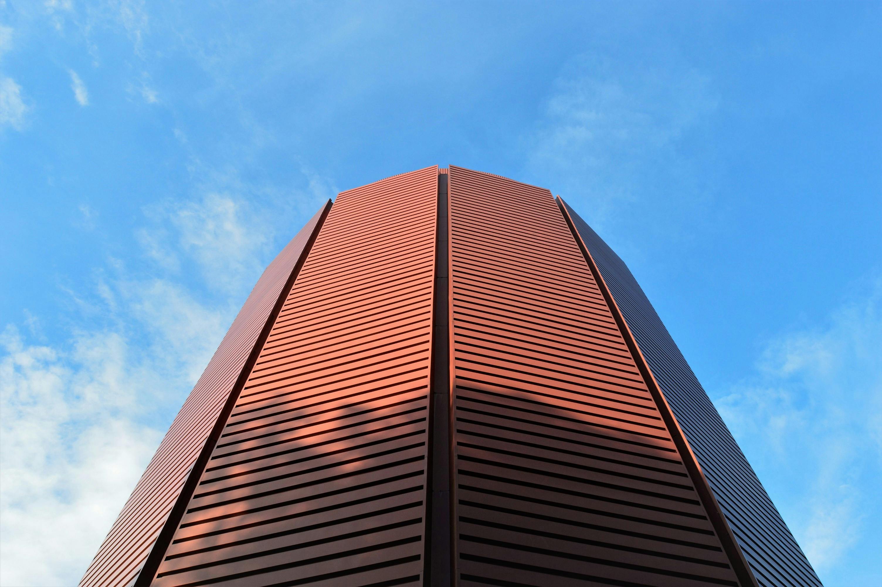 在晴朗的蓝天下，低角度拍摄的现代红色建筑线条流畅