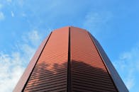 在晴朗的蓝天下，低角度拍摄的现代红色建筑线条流畅
