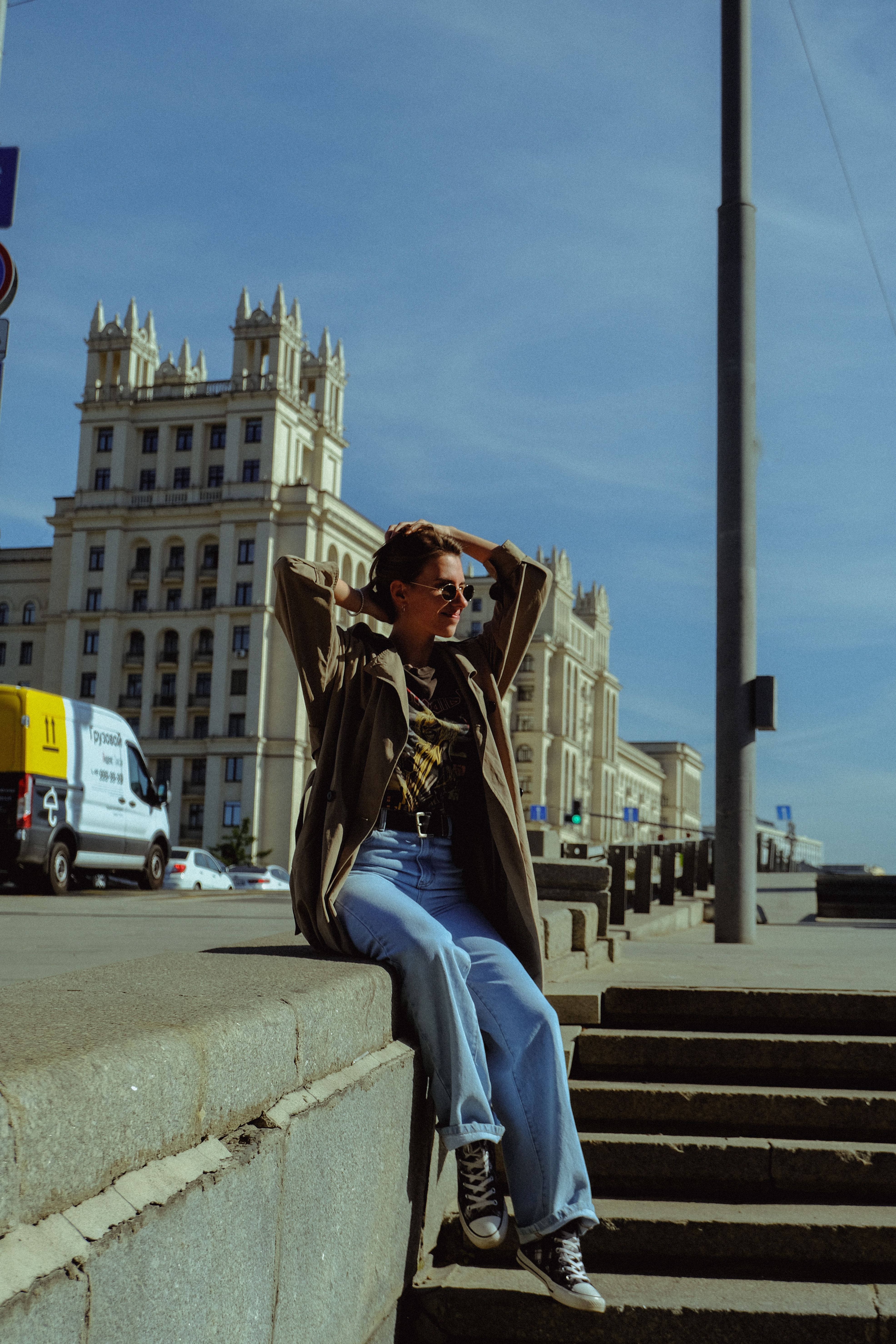 Editorial street-style photo of a woman in light-wash voluminous relaxed jeans with a trench coat and sneakers