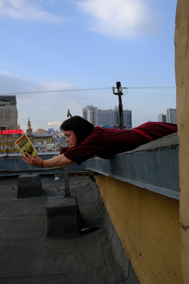 Woman Lying On Roof Edge With Book