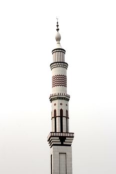A striking view of a white architectural minaret towering into an overcast sky.