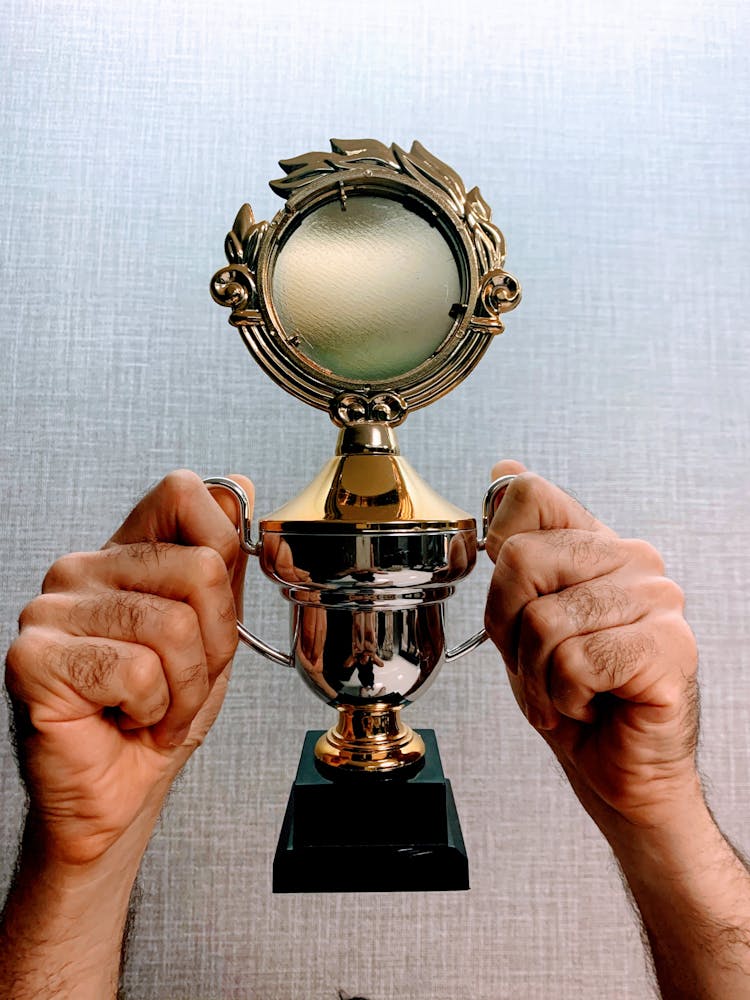 A Person Holding A Championship Trophy