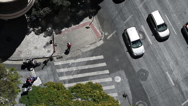 High-angle urban street scene with pedestrians, cars, and zebra crossing.