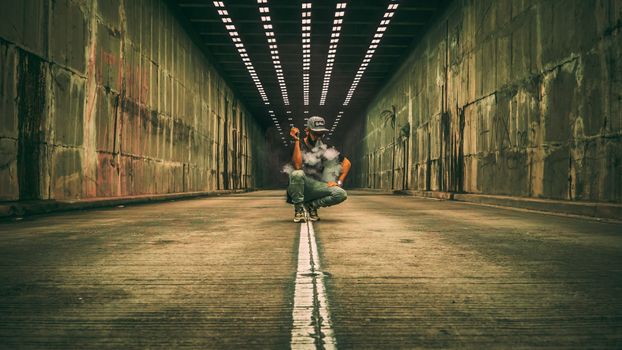 Man squats in a tunnel vaping, surrounded by smoke and moody lighting.