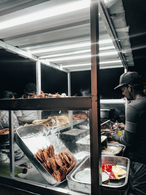 Man Wearing a Cap Selling Street Food