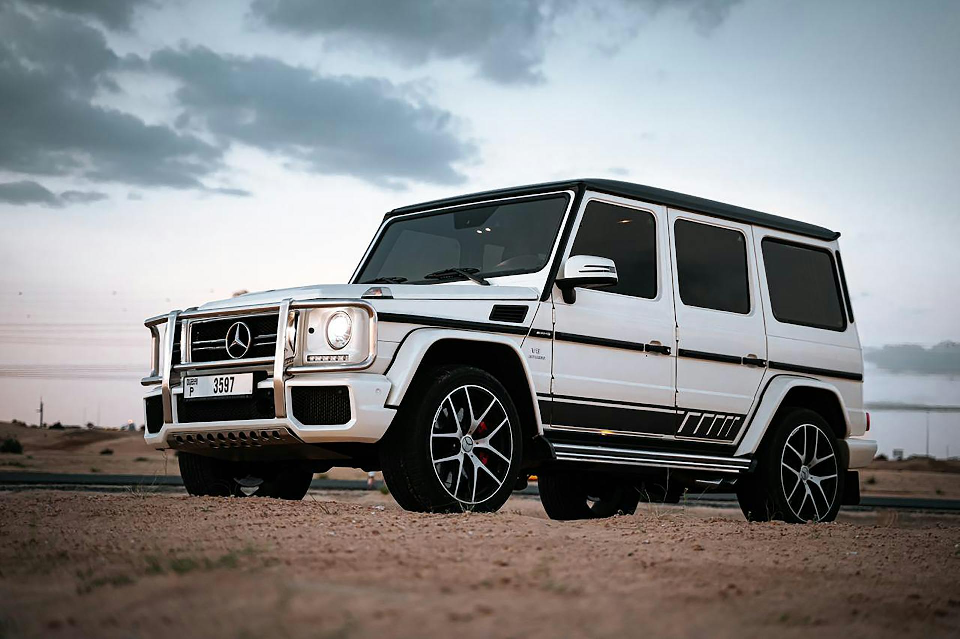 White Mercedes SUV parked on a desert terrain during daytime showcasing luxury and design.