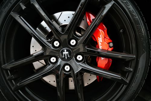 Free Stunning close-up of Maserati car wheel featuring shiny alloy rim and red brake caliper. Stock Photo