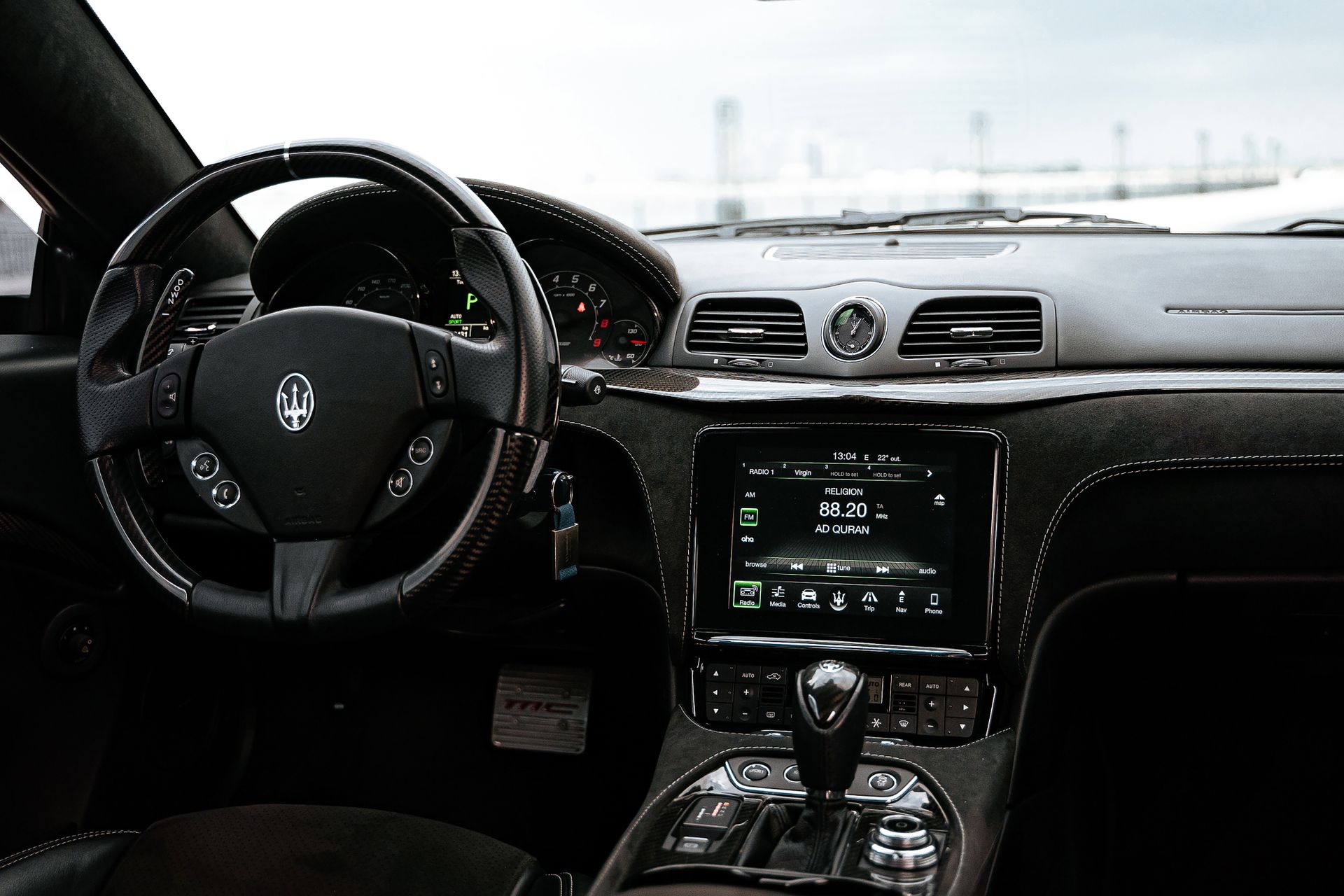 Luxurious Maserati car interior showcasing steering wheel, dashboard, and infotainment system.