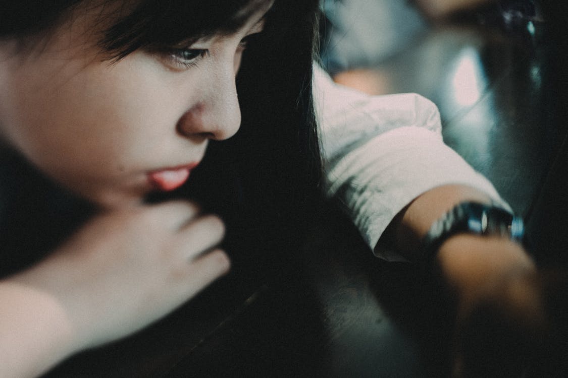 From above of crop young melancholic Asian lady in stylish clothes looking down