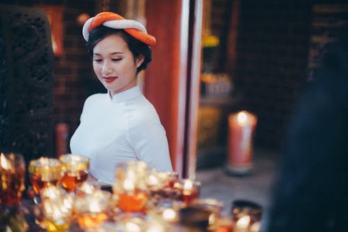 Smiling elegant Asian woman near table with shiny candles