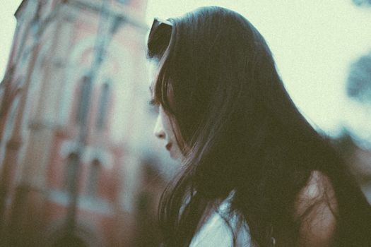 一位女人站在一座历史建筑旁，低头沉思，神情宁静而专注