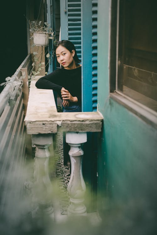 Positive Asian woman leaning on balcony railing