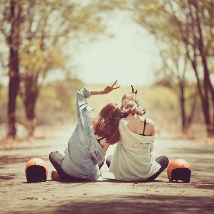 Two friends sitting together on a tree-lined road — photo by Khoa Vo on Pexels
