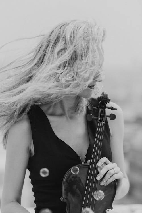 Black and white female musician holding music instrument while blowing hair on wind