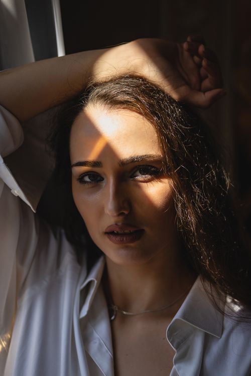 Free Striking portrait of a woman in white shirt with dramatic light creating shadows. Stock Photo