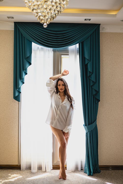 Woman in White Button Up Shirt Standing Beside Window