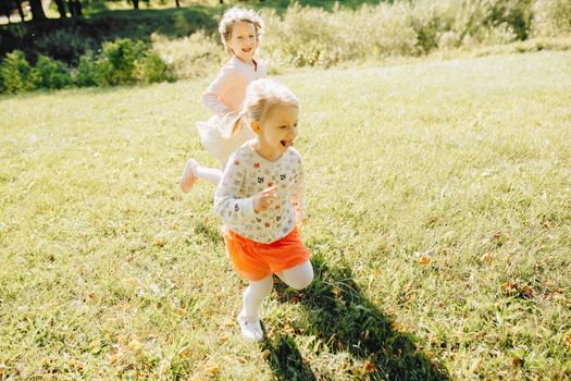 Two young girls laughing and playing on a sunny day in the park.