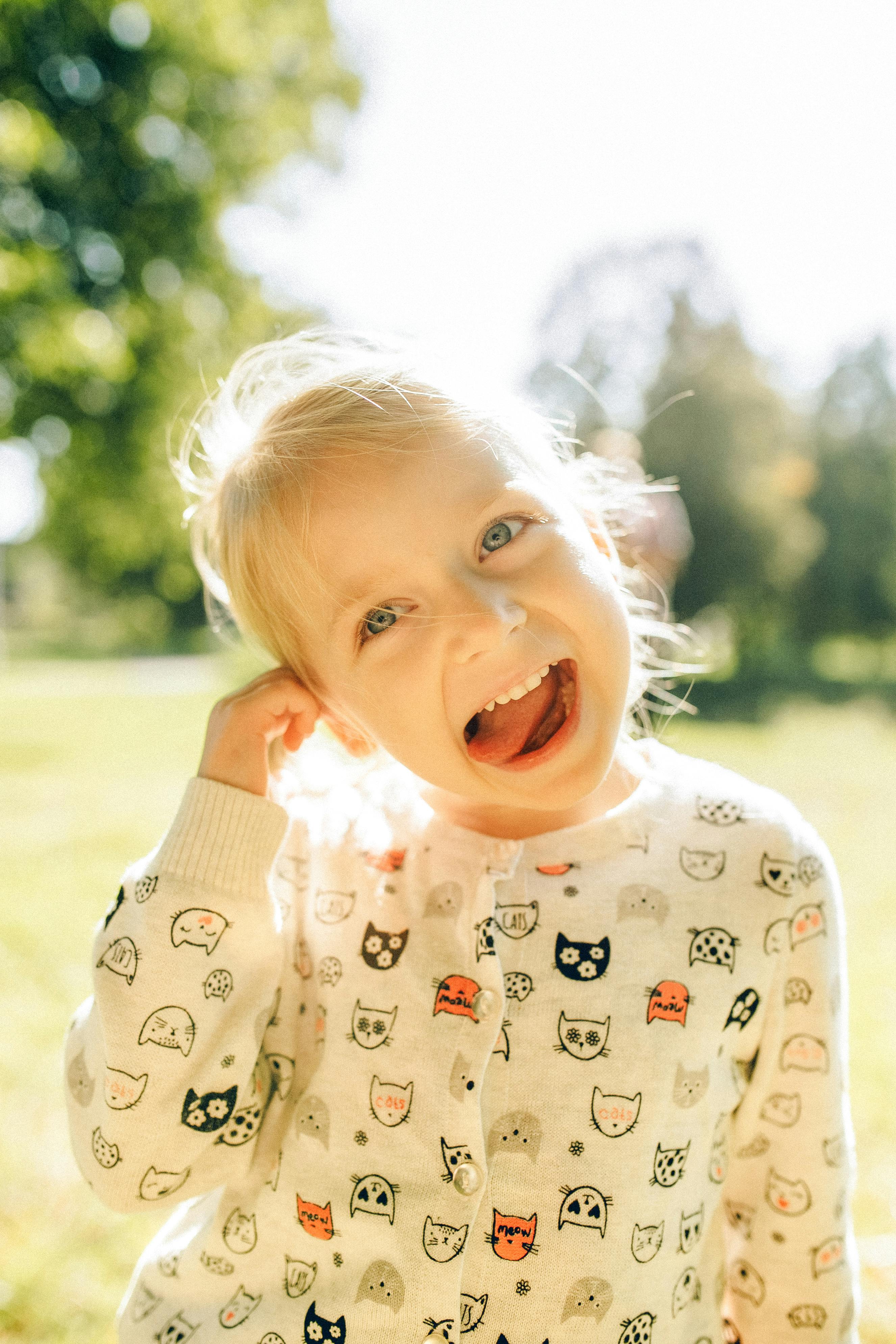 在阳光明媚的户外公园里，穿着可爱的猫印花上衣大笑