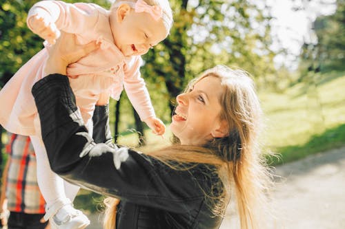 Free Woman in Black Long Sleeve Shirt Carrying Baby in Pink Jacket Stock Photo