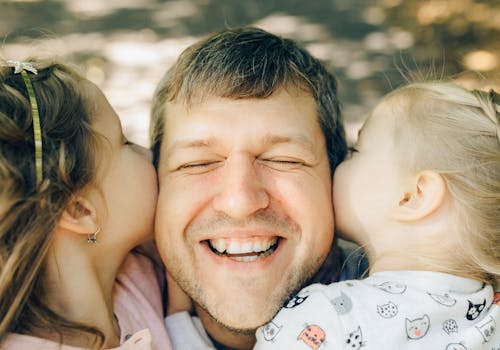 Close-up of a Man being Kissed by his Daughters