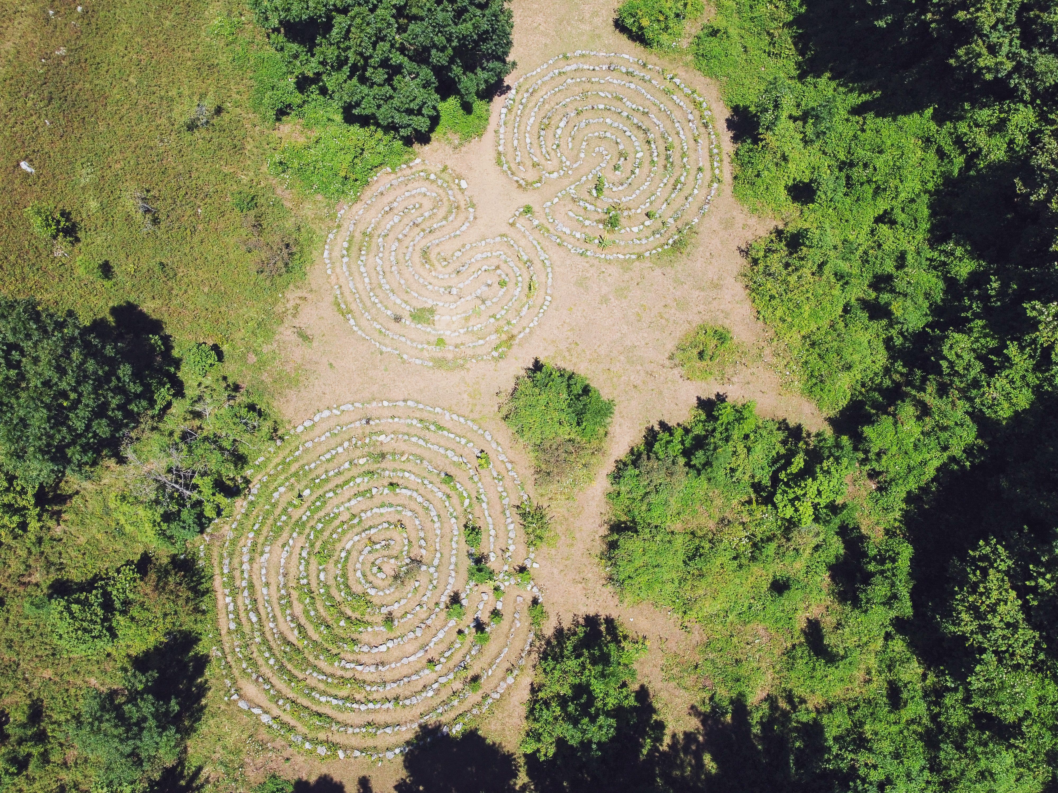 Aerial photograph showing three stone labyrinths set within a lush green forest clearing.