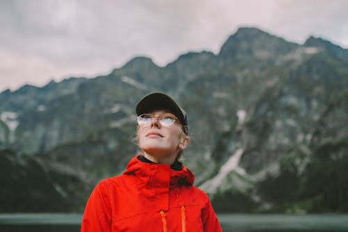 Close-up Photo of Woman in Red Windbreaker Jacket and Eyeglasses 