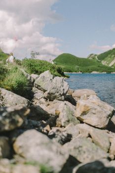 风景如画的湖畔，宁静的海水映衬着岩石、郁郁葱葱的山丘和晴朗的天空