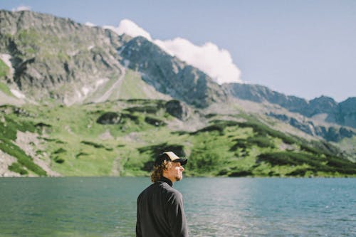 Free A Man Wearing a Cap while Standing Near the Body of Water Stock Photo