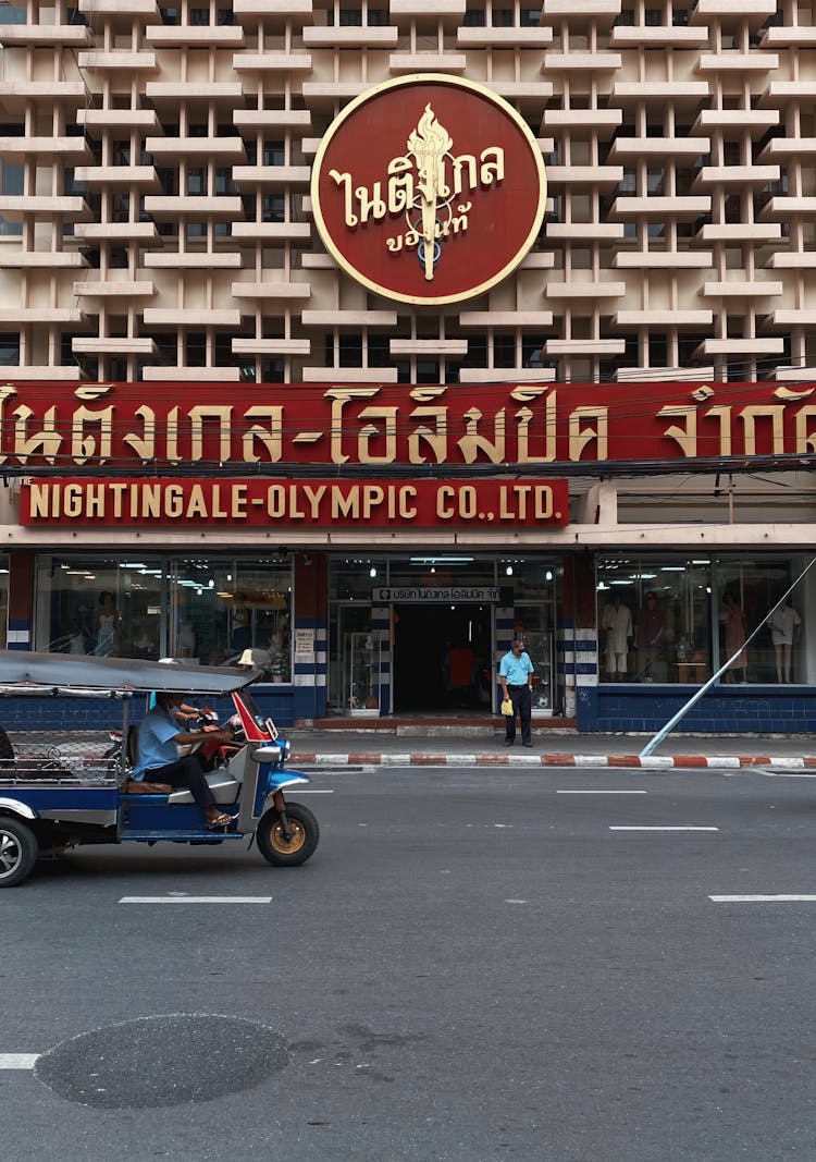 Modernist Building Facade With Thai Script And Rickshaw On Street