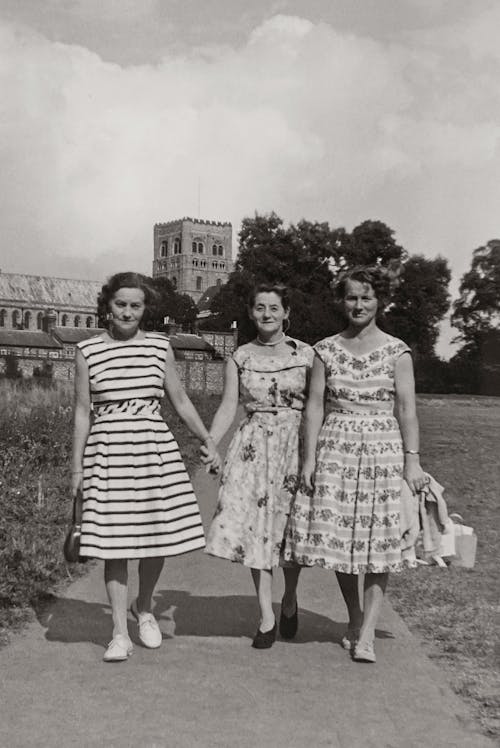 Grayscale Photo of Women Walking Together On A Pathway In A Field