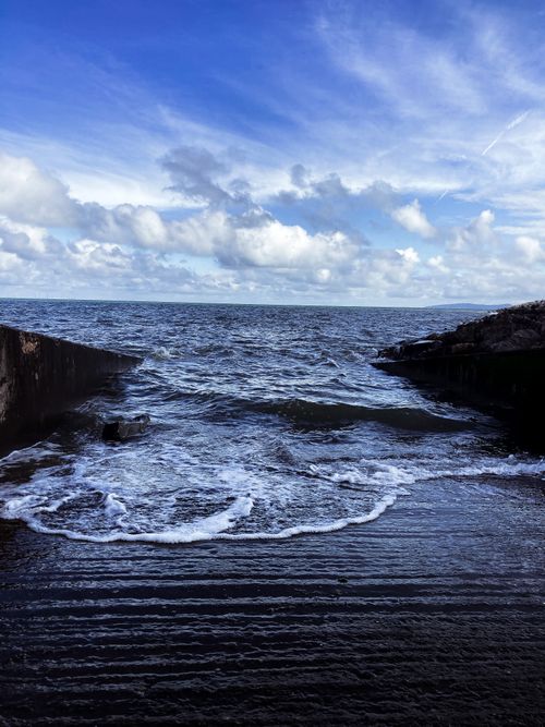 Free Vibrant blue sky covered with clouds above dark wavy endless ocean and slope on coast Stock Photo