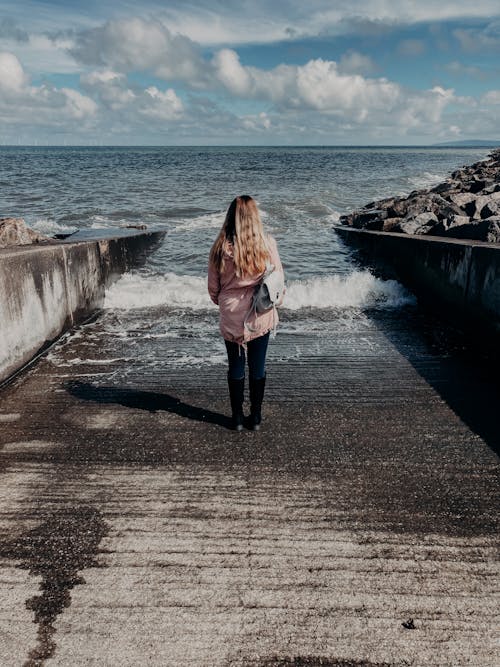 Free Anonymous woman standing on embankment and looking at sea Stock Photo
